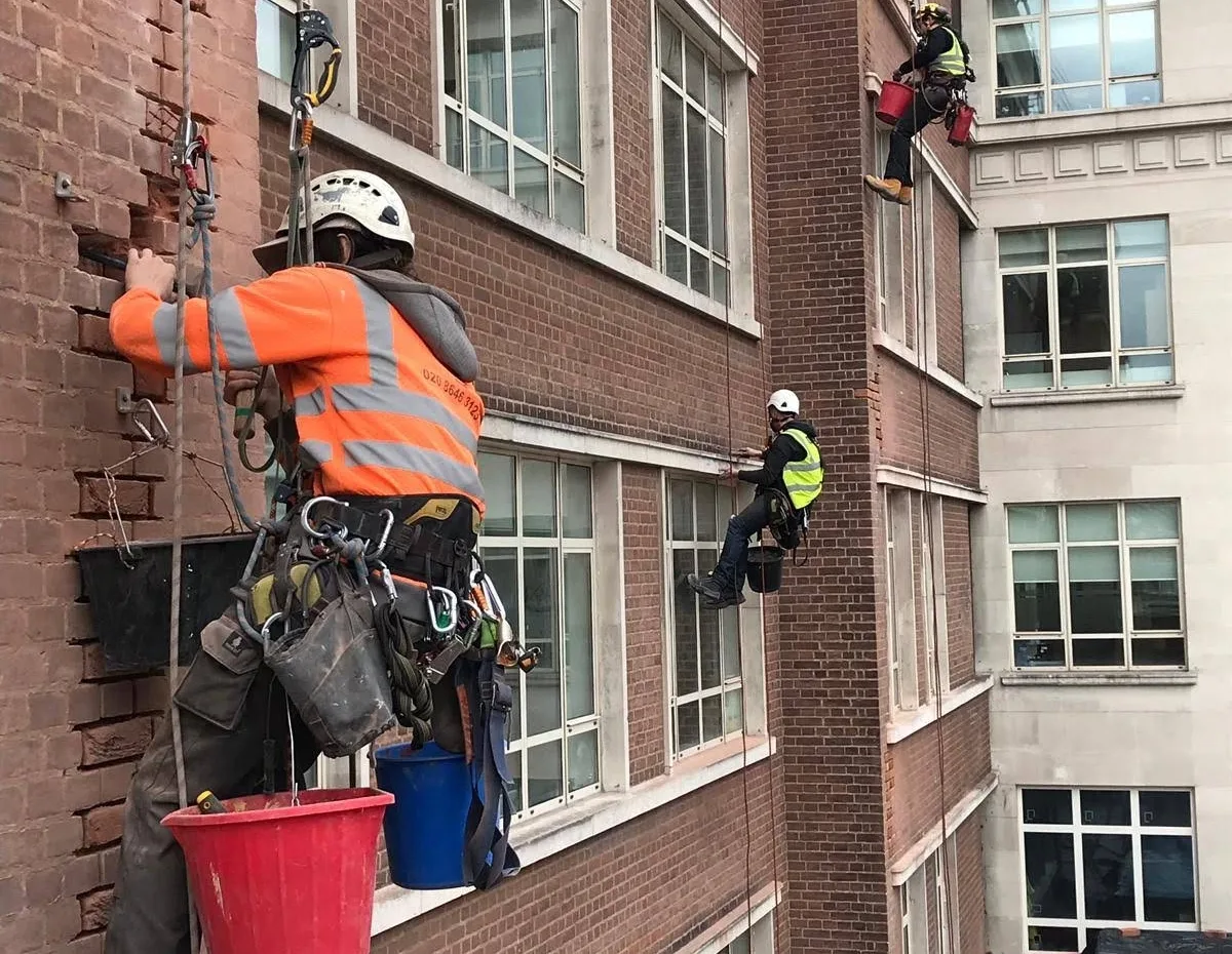 Rope access technicians carrying out brick and masonry repairs on a London building, ensuring structural integrity.