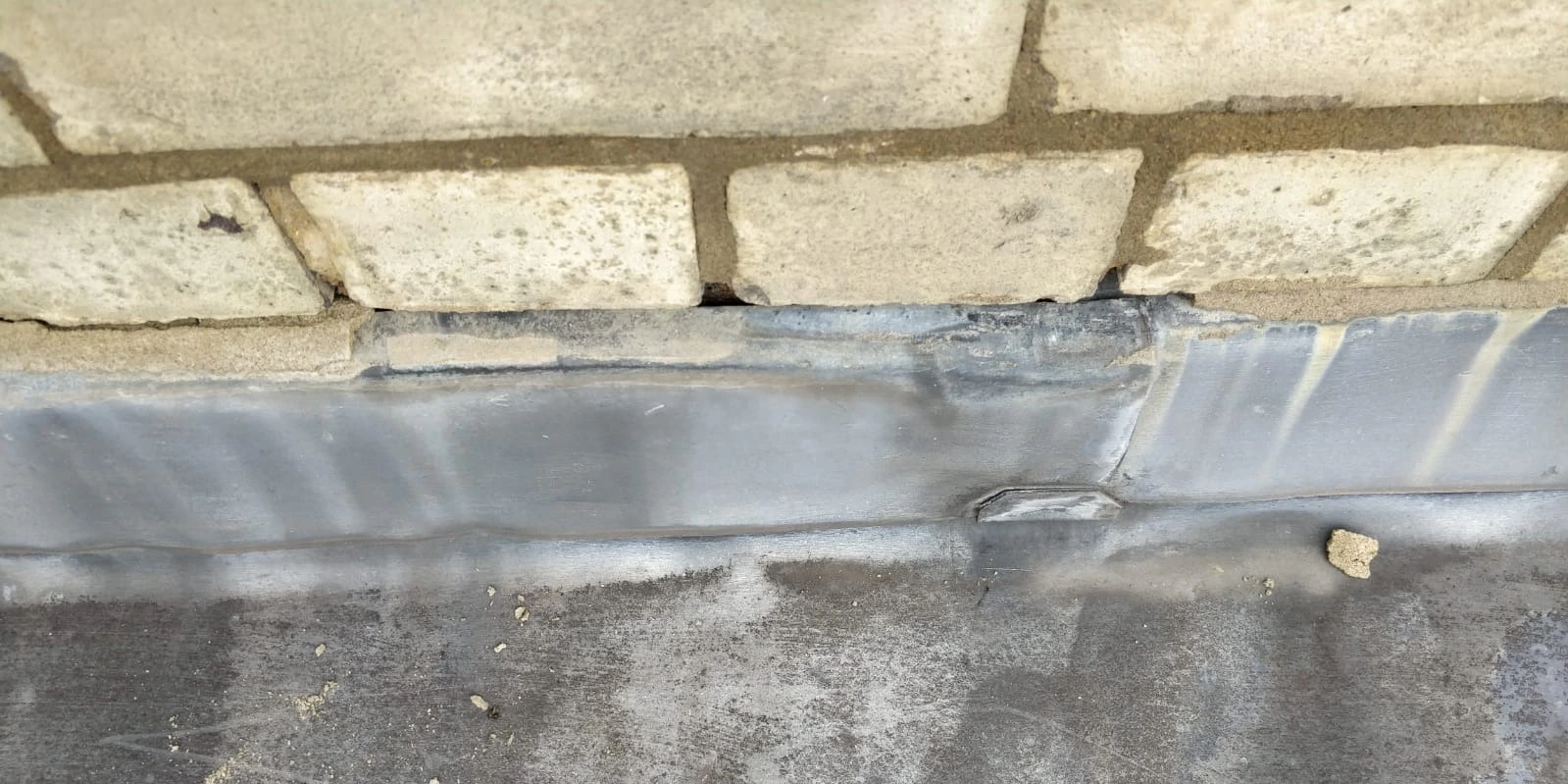 Close-up of deteriorating lead flashing with visible cracks and gaps, requiring professional repair to prevent water ingress and structural damage.