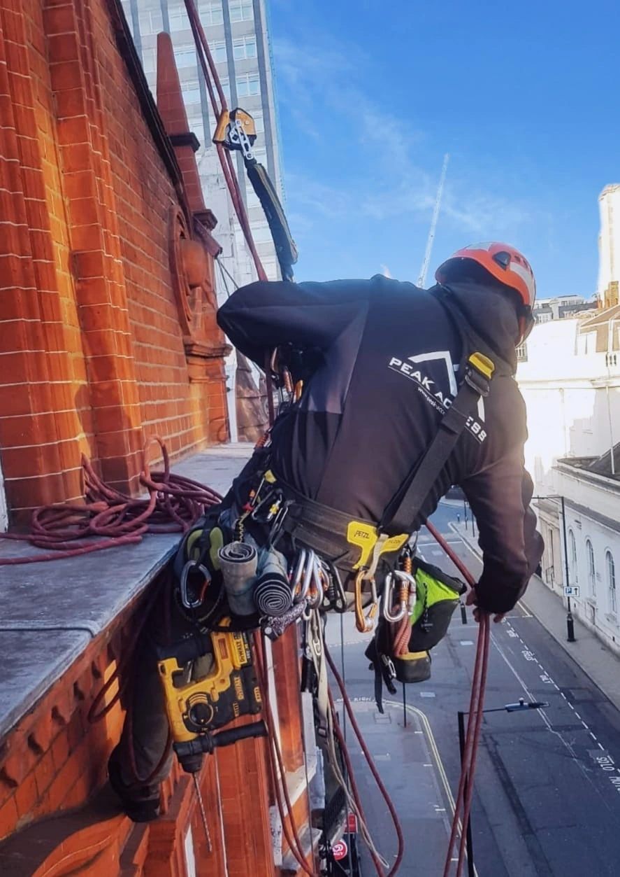 Rope access technicians installing and inspecting an anchor system on a high rise building in London to ensure safe work at height