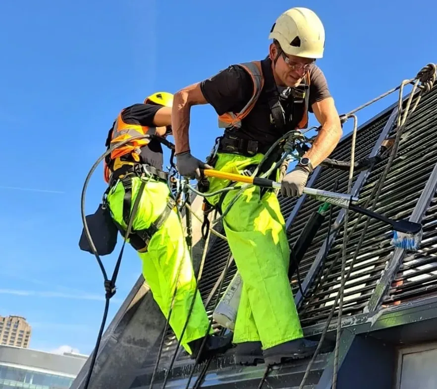Rope access technicians carrying out cleaning on a high rise building in London to remove dirt and debris from the facade
