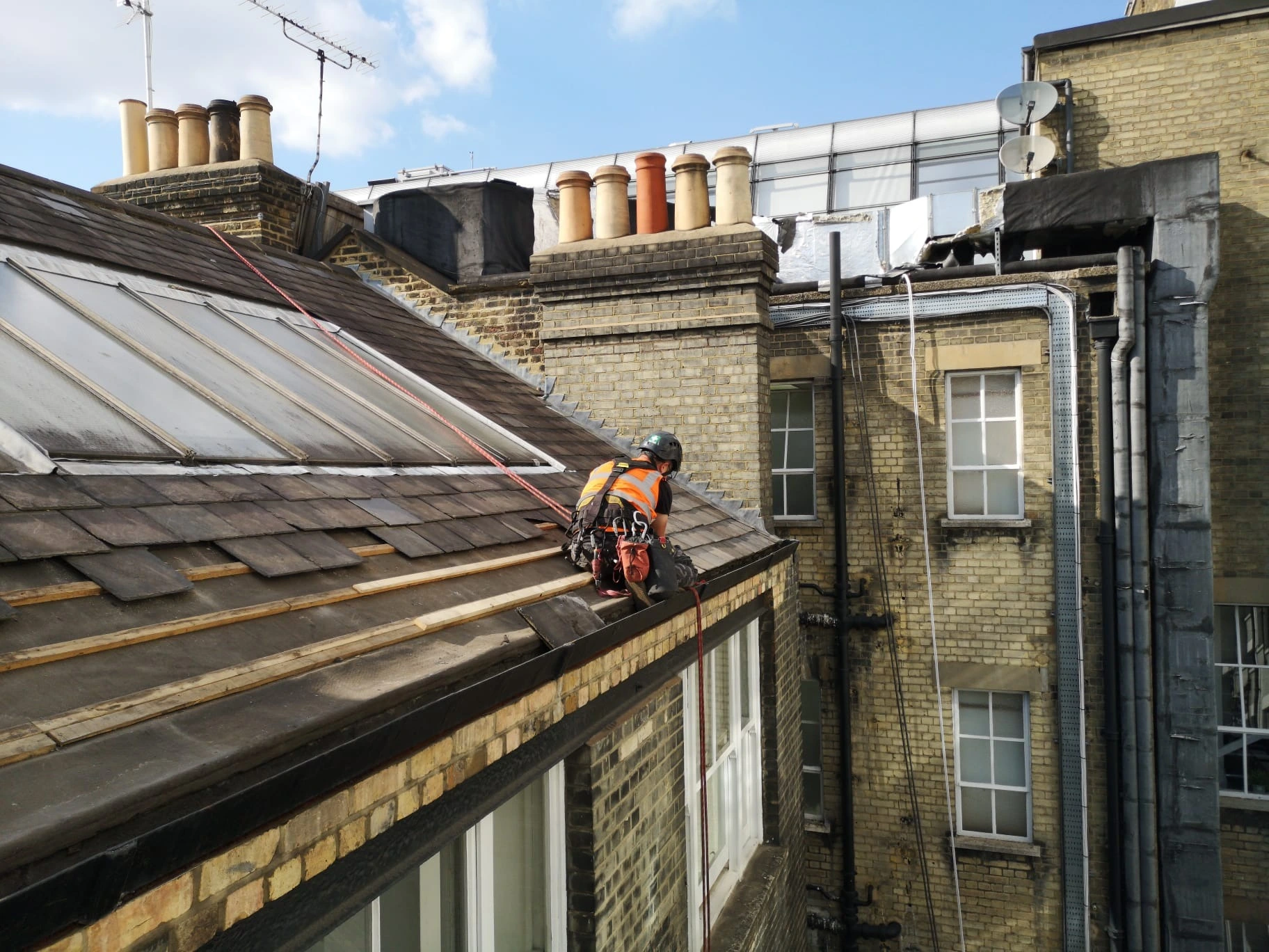 Rope access technicians carrying out commercial roofing work on a high rise building in London to maintain repair and protect the roof structure