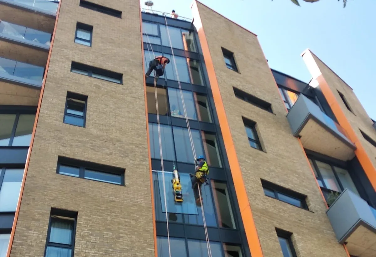 Rope access technicians carrying out high level glazing replacement on a building in London to install new glass panels and ensure structural integrity