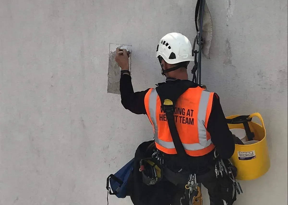 Rope access technicians carrying out terrace waterproofing on a high rise building in London to protect surfaces from water ingress and weather damage